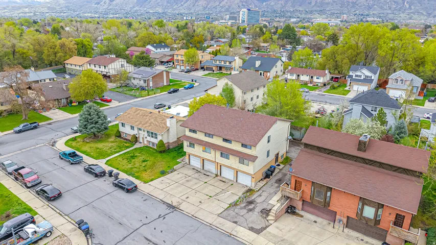 Multi-unit property with a brick and stucco exterior, featuring multiple garage bays and a brown shingle roof