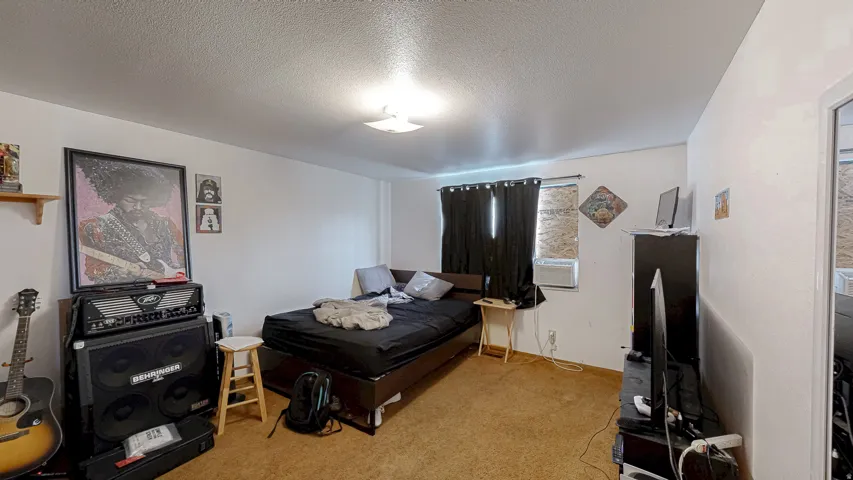 Expansive room featuring light-toned walls, a textured ceiling, and a ceiling-mounted light fixture