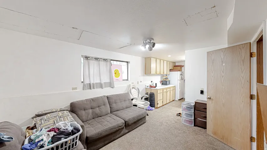 Open-concept living space featuring carpet flooring, white walls, and a multi-light flush mount ceiling fixture