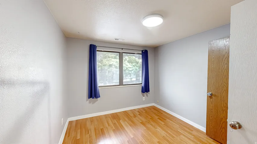 Room featuring wood-finish flooring, a window with natural light, and a flush-mount ceiling light fixture