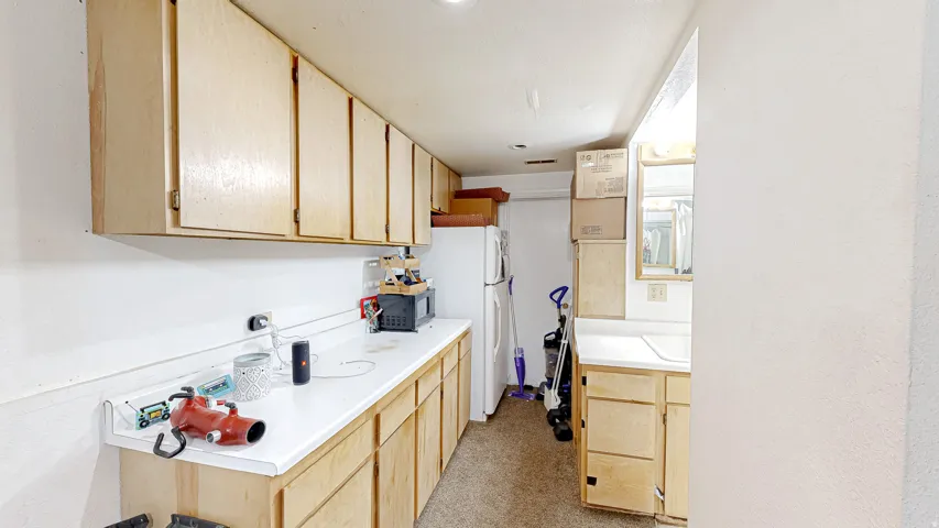 Functional utility space featuring extensive light wood cabinetry, white laminate countertops, and a built-in sink area