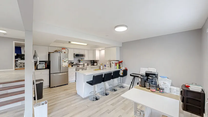Kitchen featuring wood-finish flooring, white cabinetry, a central island with countertop seating, stainless steel appliances, and recessed lighting