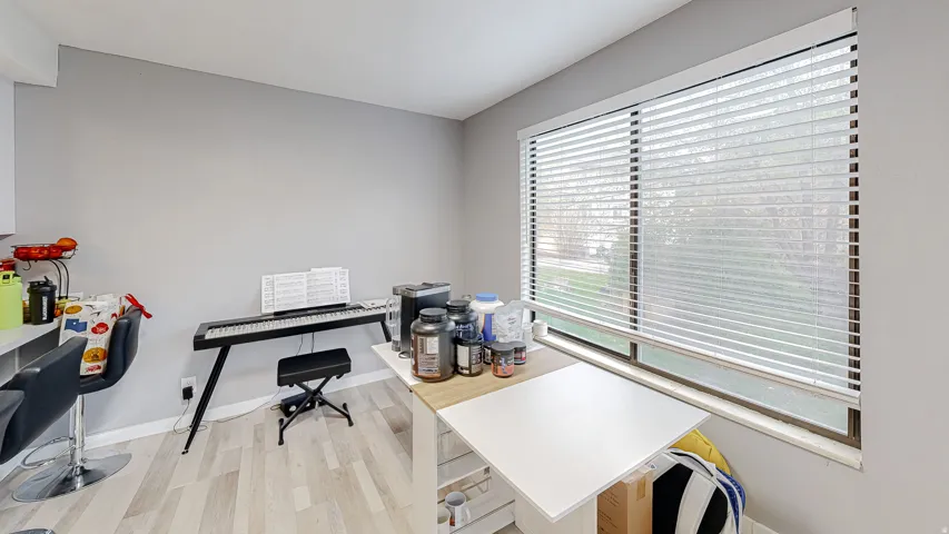 Interior space featuring light gray walls, wood-finish flooring, and a large window with horizontal blinds