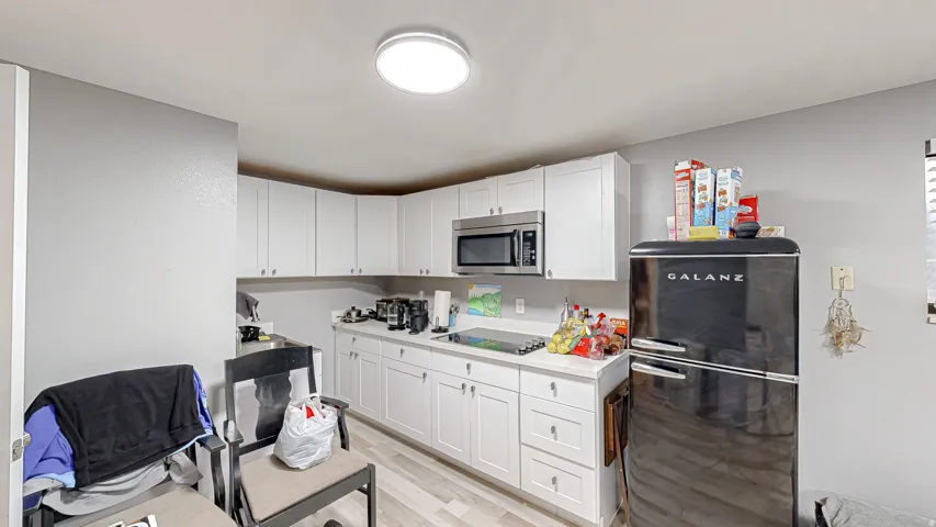 Kitchen featuring white cabinetry, light-toned countertops, wood-finish flooring, and a stainless steel microwave