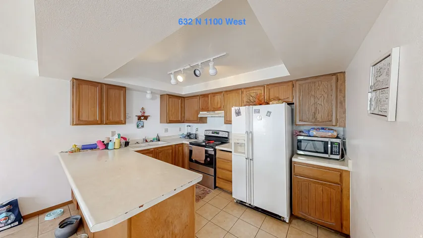 Kitchen featuring extensive wood cabinetry, L-shaped countertop, tile flooring, and track lighting