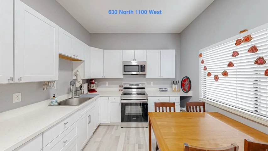 Kitchen with white shaker-style cabinetry, stainless steel appliances, and light-toned countertops