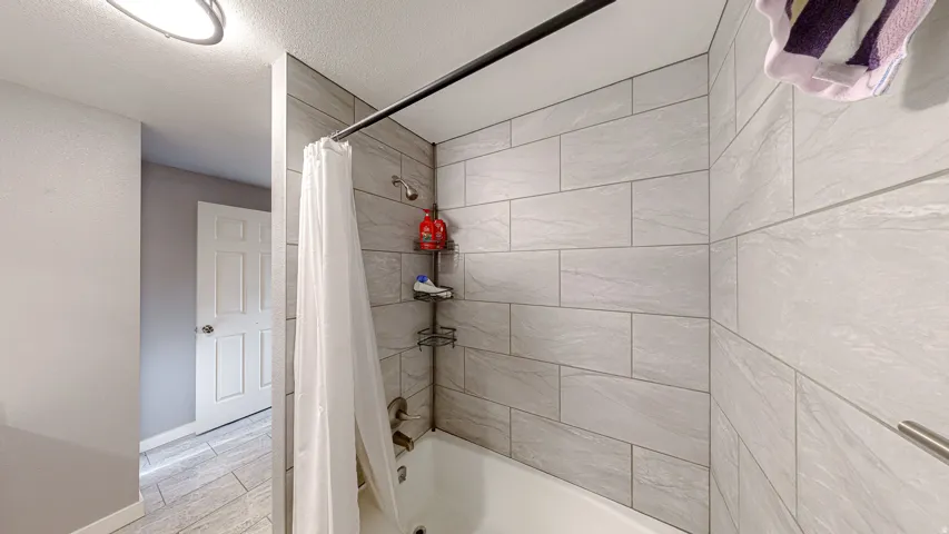 Bathtub with subway tile surround, ceiling-mounted showerhead, and wall-mounted shower faucet