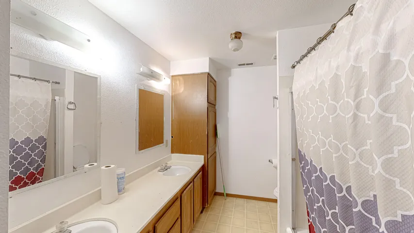Bathroom featuring a double vanity with integrated sinks, a wood-finish cabinet, and a built-in linen tower