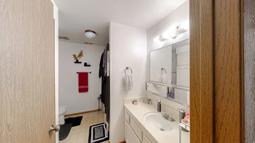 White vanity with integrated sink, chrome faucet, and overhead bar lighting