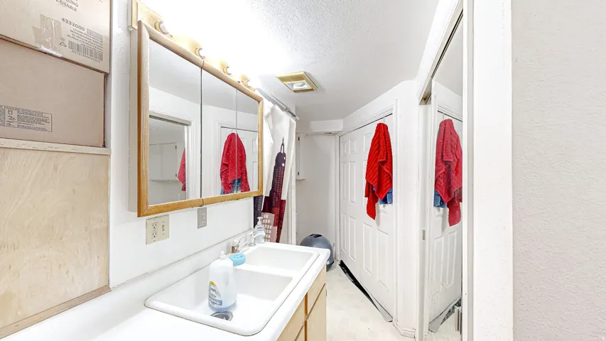 Bathroom vanity featuring a double basin sink, expansive countertop, and wood-framed medicine cabinet with integrated lighting