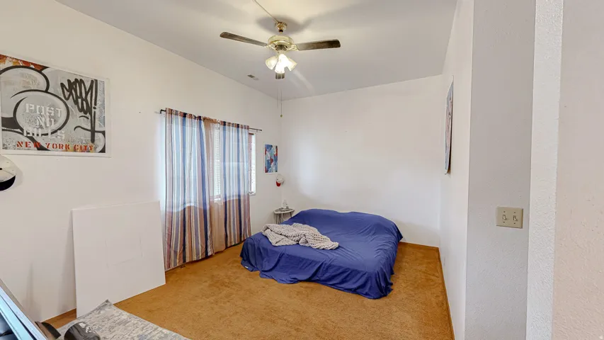 Carpeted room with a ceiling fan light fixture