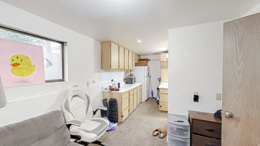 Compact kitchen area with light wood-finish cabinetry and a white countertop