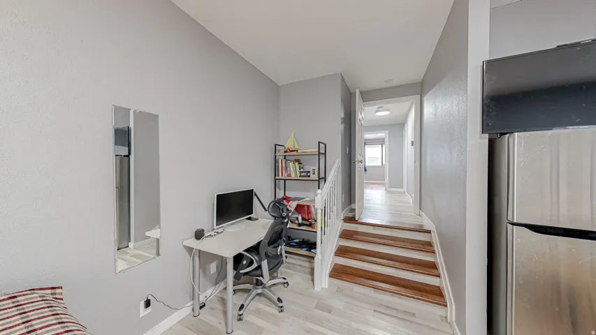 Lower level space featuring light wood-finish flooring, light gray wall paint, and a built-in staircase with wood treads