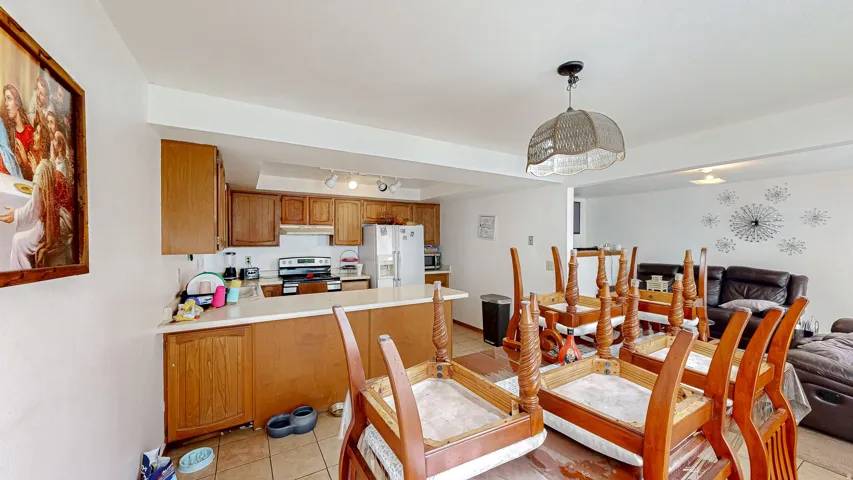 Kitchen and dining area featuring wood-finish cabinetry, a light-toned countertop, and tile flooring