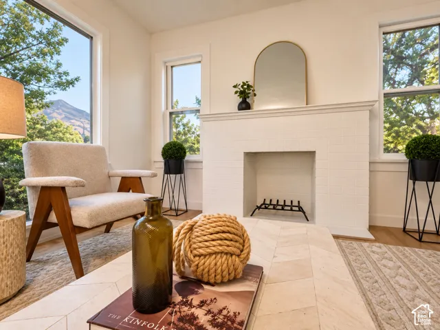White brick-tiled fireplace with hearth, complemented by a prominent window featuring a mountain backdrop