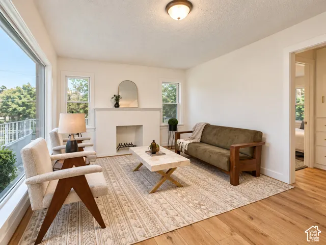 Recessed fireplace with mantel, expansive window-lined wall, wood-finish flooring, and a ceiling-mounted light fixture