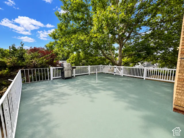 Spacious rooftop patio featuring 418 square feet of entertaining space with white railing, and surrounding mature trees