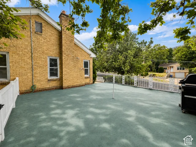 Expansive outdoor patio area featuring a white decorative metal fence and vinyl gate leading to backyard.