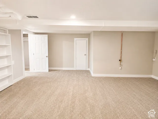 Spacious family room featuring neutral carpeting, light-toned wall paint, and white trim