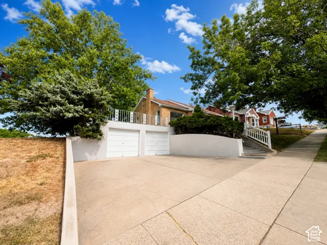 Property entrance featuring a two-car garage, concrete driveway, and a white railing leading to the residence
