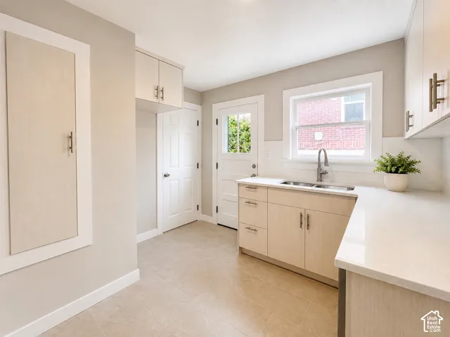 Kitchen featuring custom light wood-finish cabinetry, quartz countertops, and a custom spice cabinet