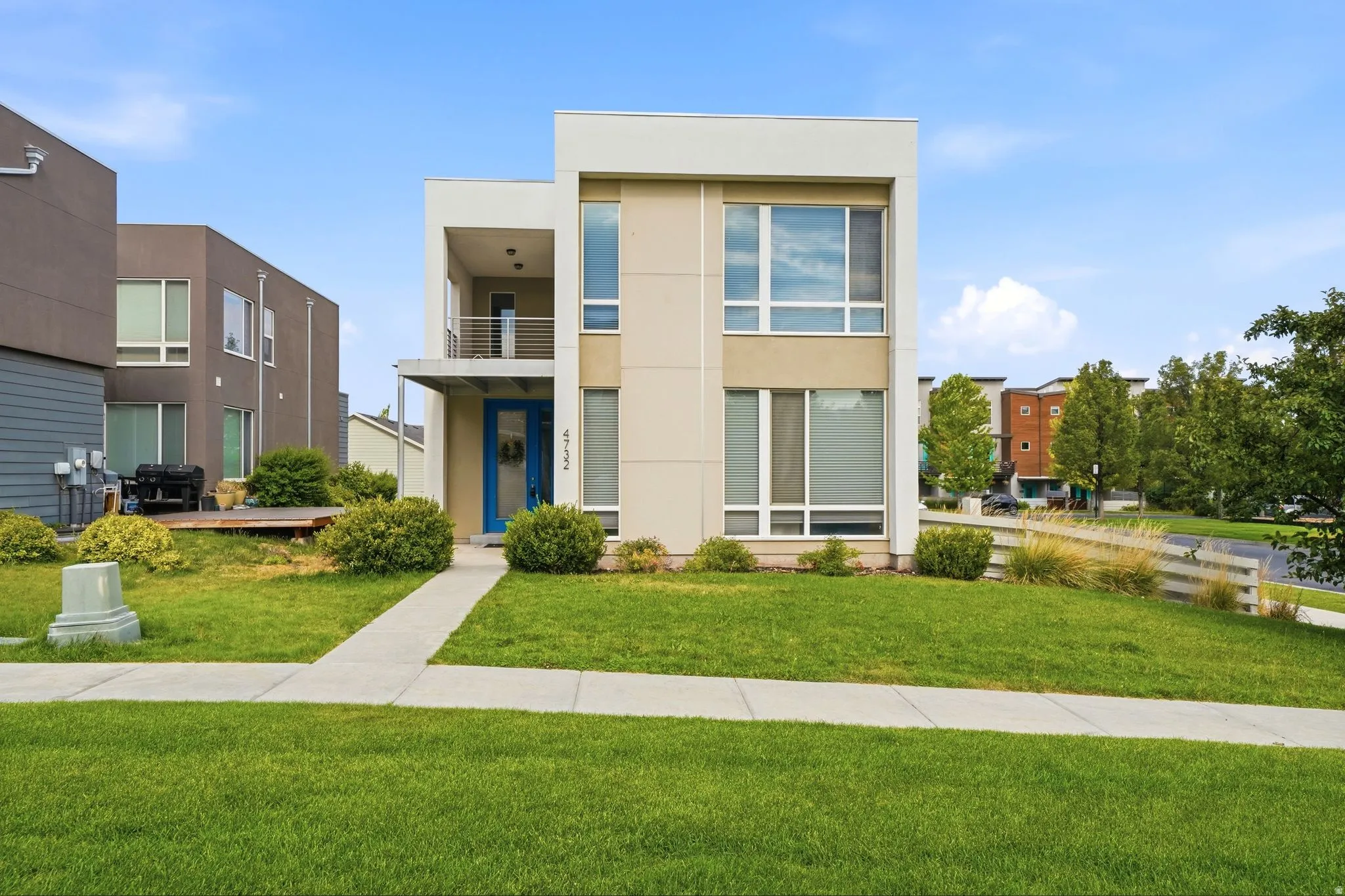 Modern multi-story facade featuring light-colored stucco and a contrasting blue front door