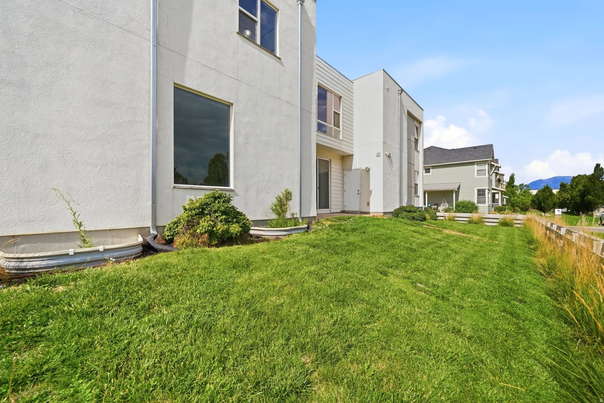 Contemporary architectural design featuring a textured stucco exterior and a sloped grass lawn