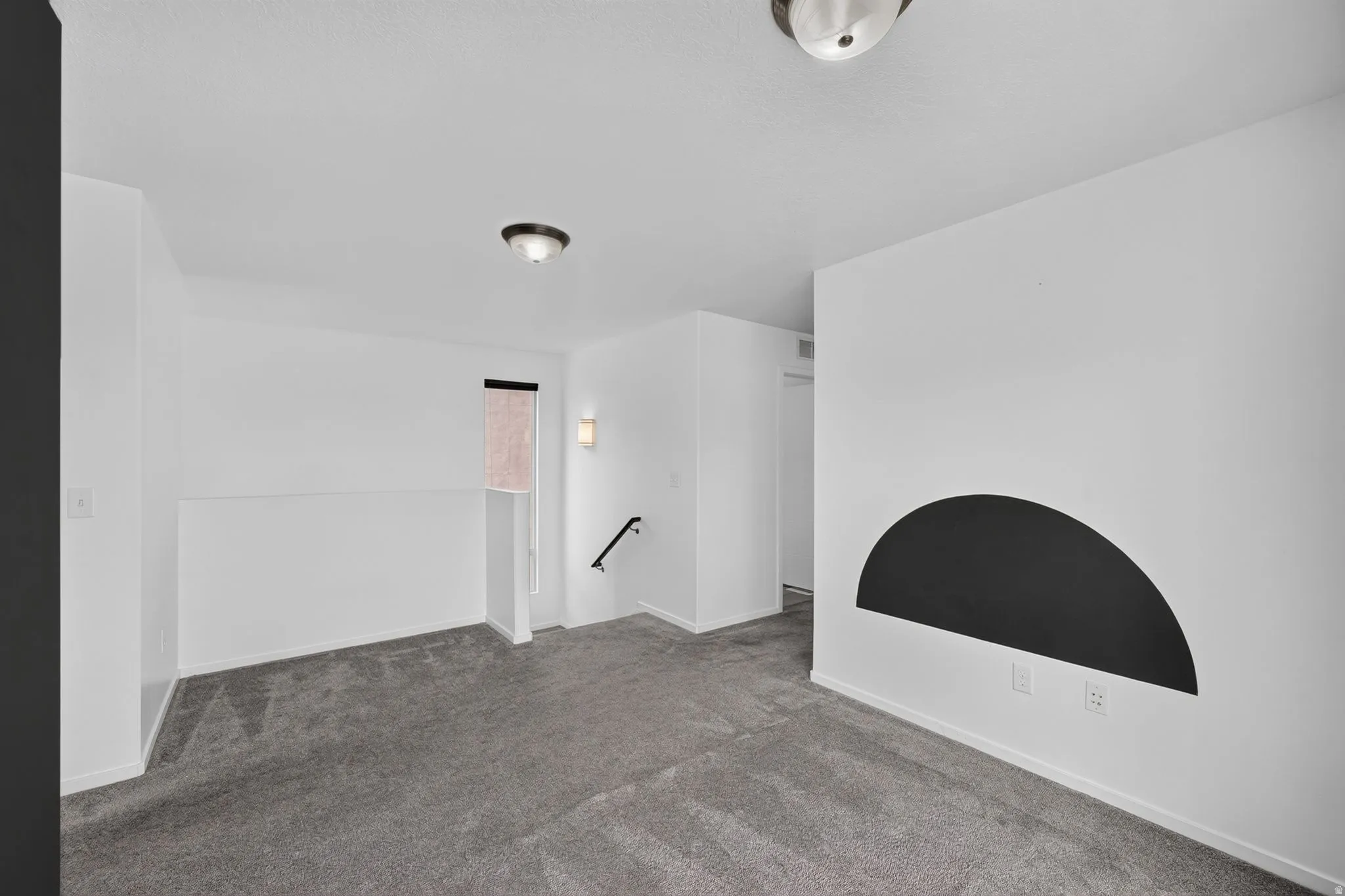 Carpeted loft area featuring crisp white walls and gray carpeting.