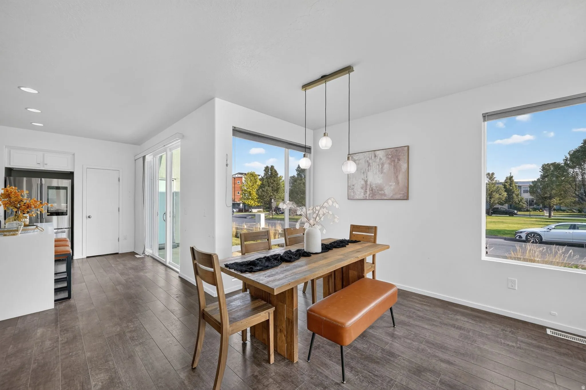 Dining area featuring wood-finish flooring, a contemporary linear pendant light fixture, and expansive windows
