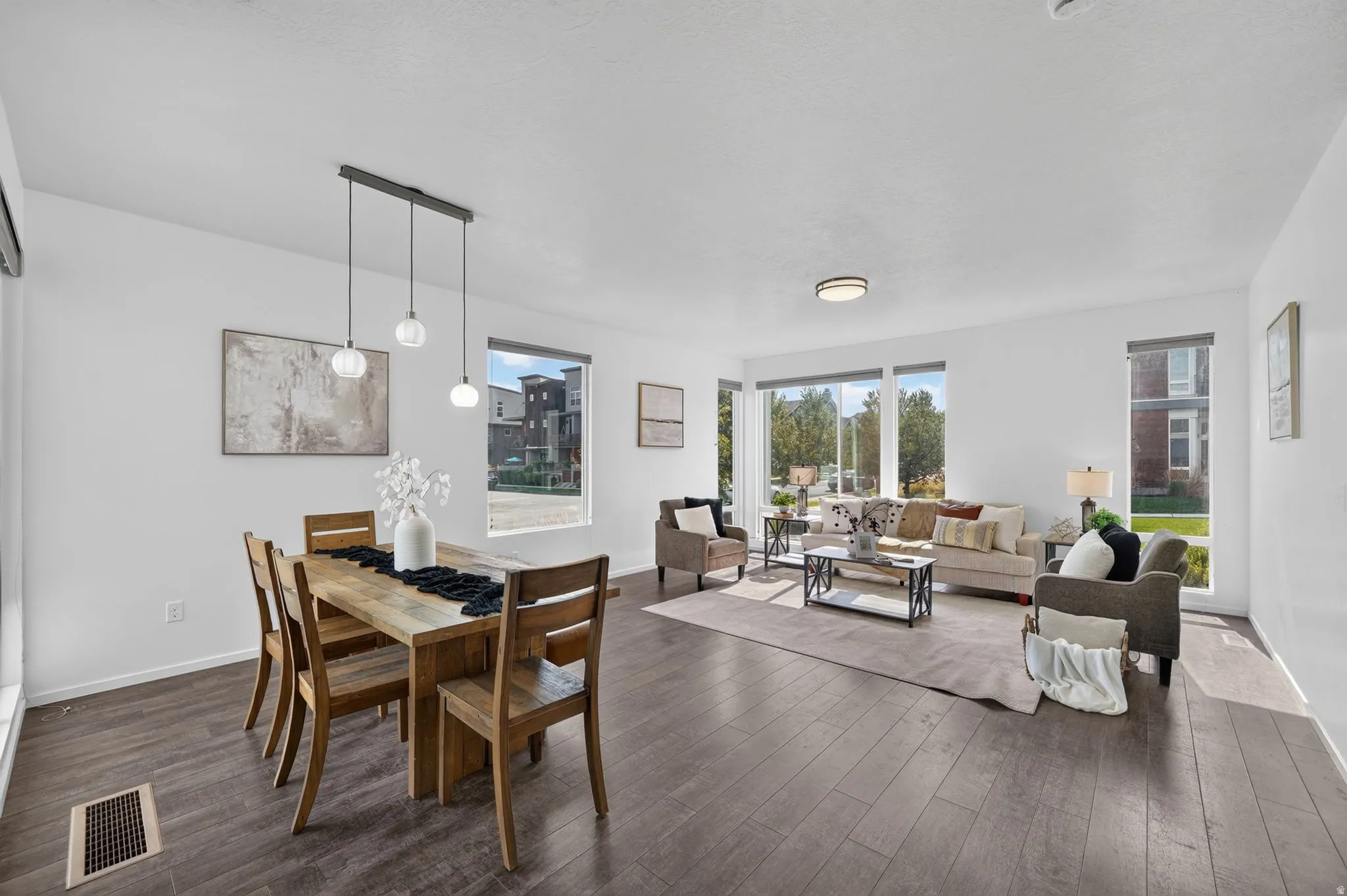 Open-concept living area with wood-finish flooring, abundant natural light, a modern linear pendant light fixture, and recessed lighting