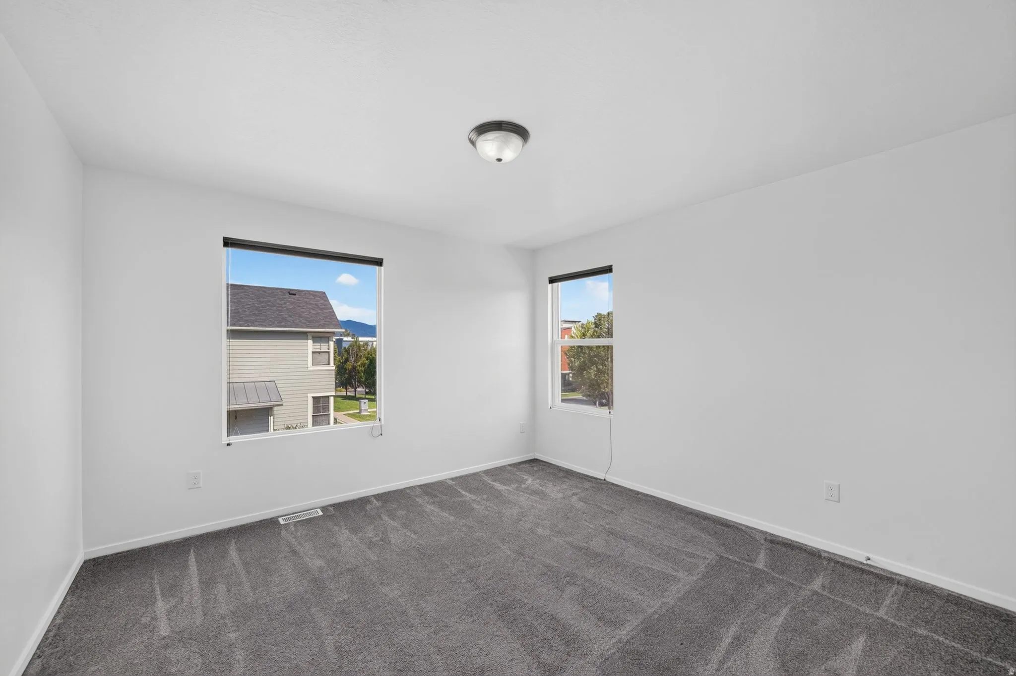 Room featuring neutral wall tones, gray patterned carpeting, and a flush-mount ceiling light fixture
