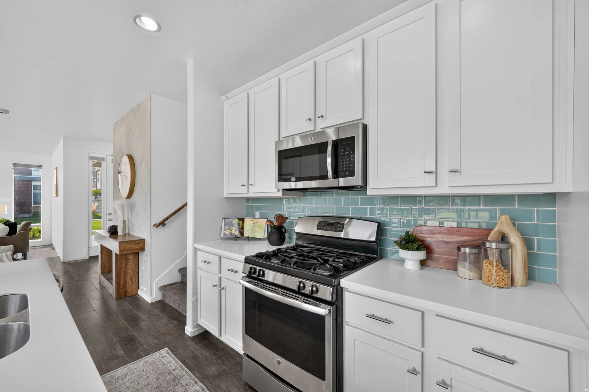 Contemporary kitchen featuring white cabinetry, stainless steel appliances, a gas range, and a blue subway tile backsplash