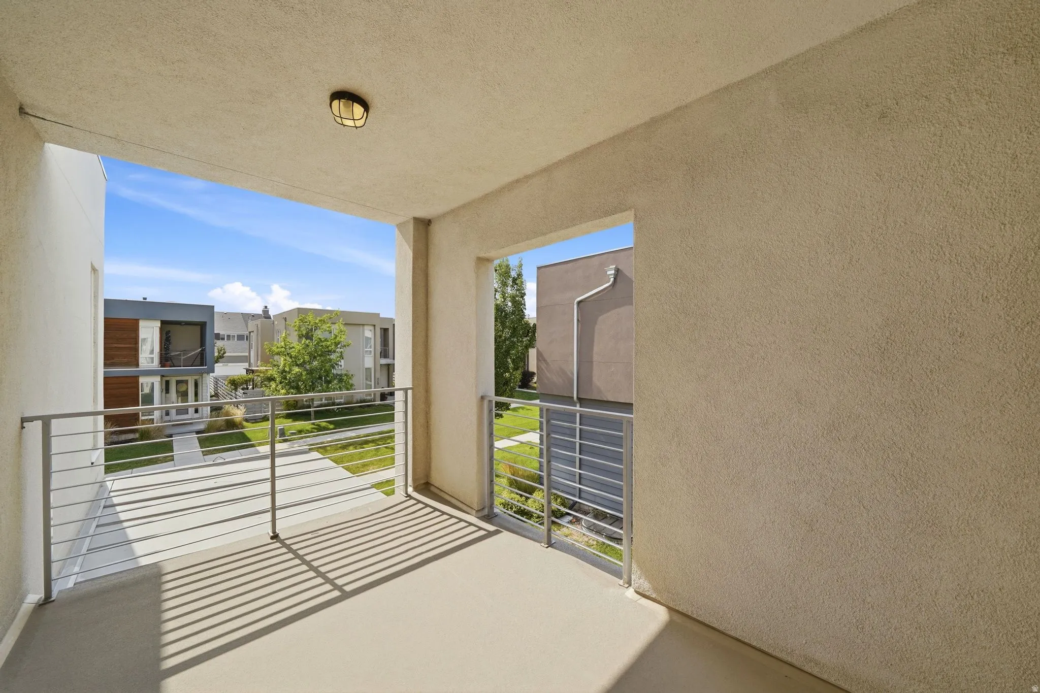 Outdoor balcony with smooth stucco walls and a cream-colored concrete floor