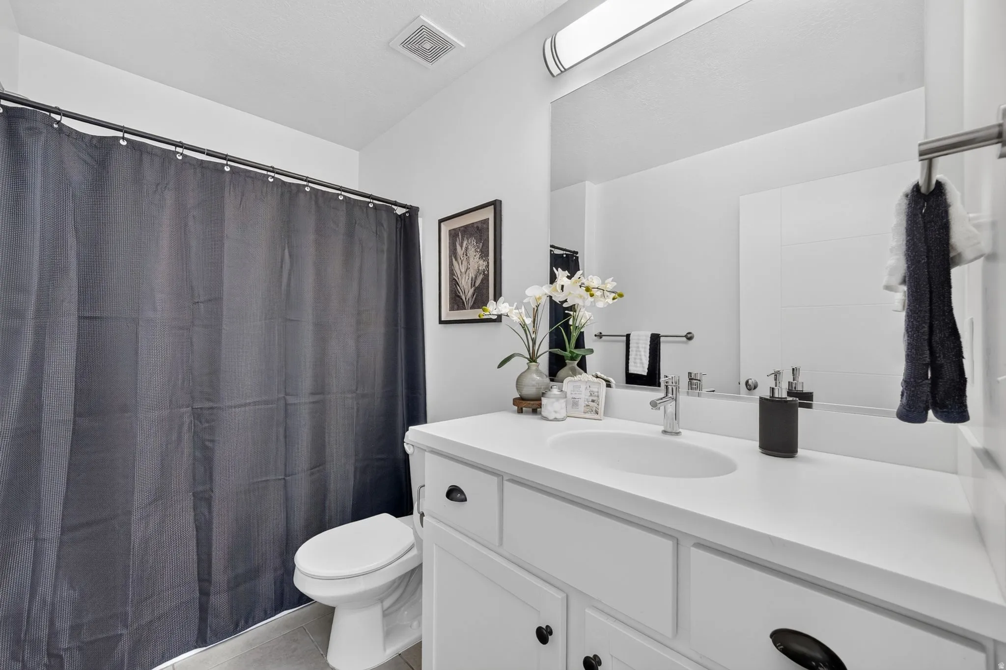 Bathroom featuring a white vanity with integrated sink, chrome faucet, and expansive mirror