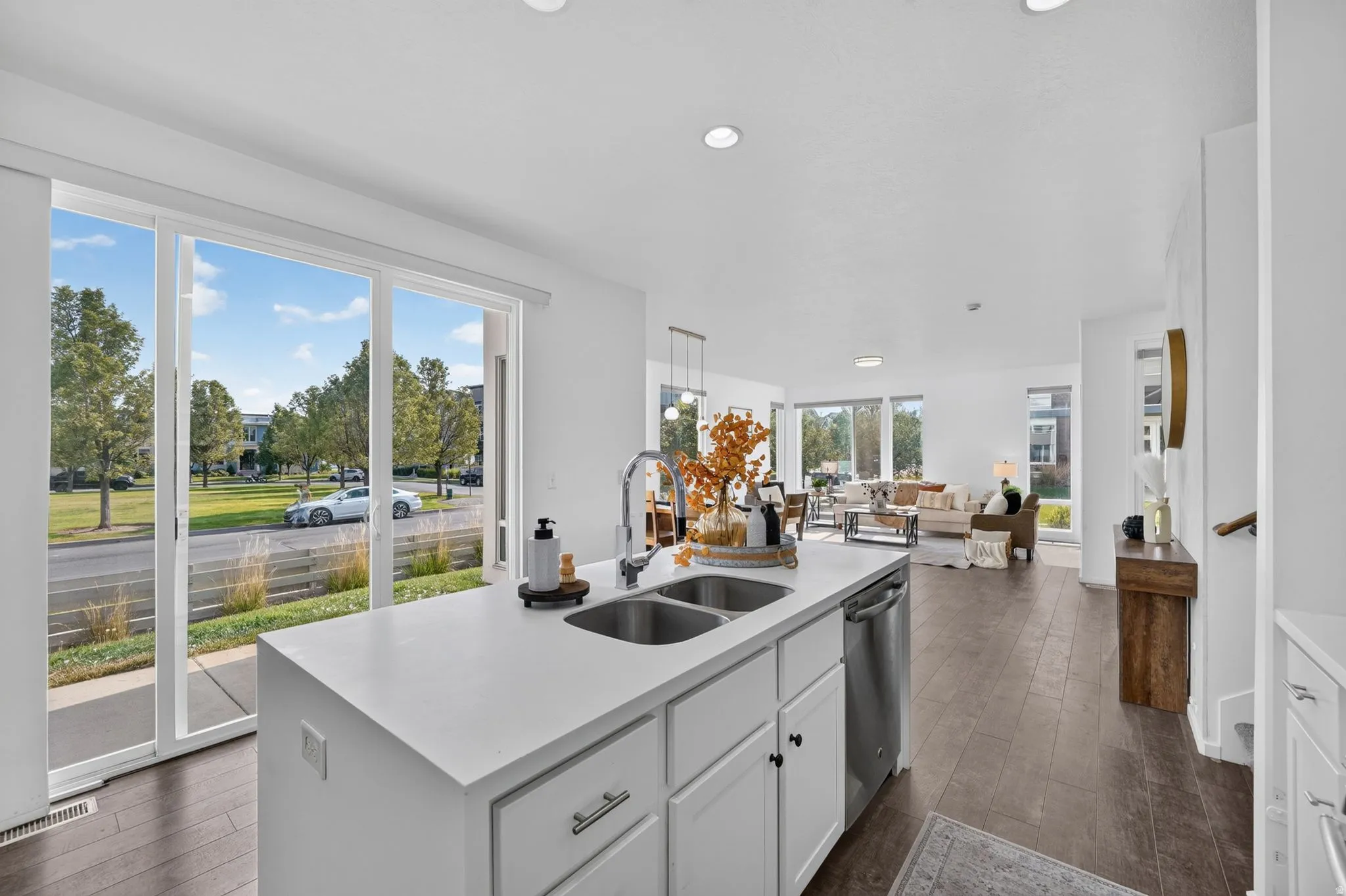Open-concept living area featuring a kitchen island with dual sinks and stainless steel dishwasher