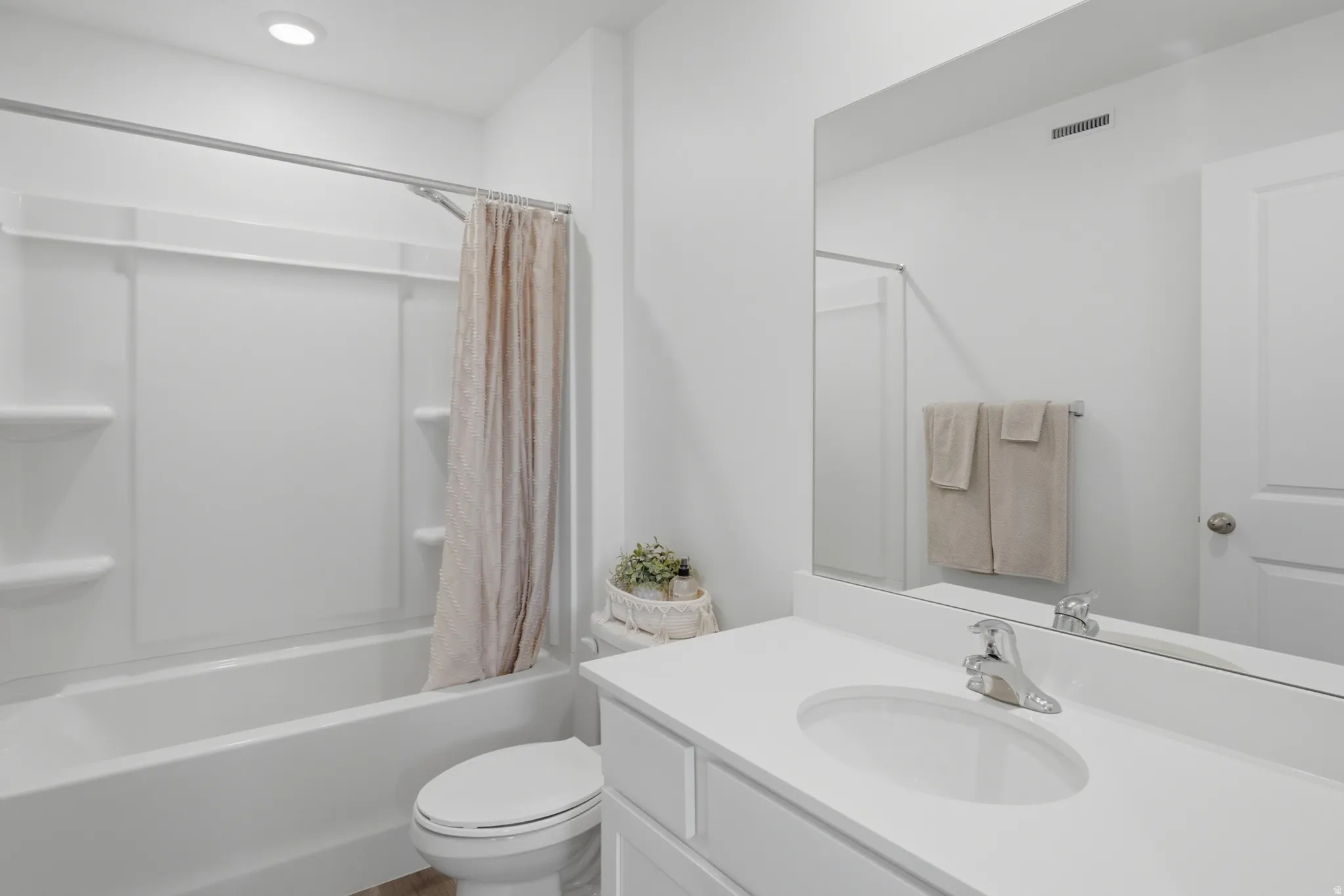 Bathroom featuring a white vanity with an integrated sink, chrome faucet, and a large wall-mounted mirror