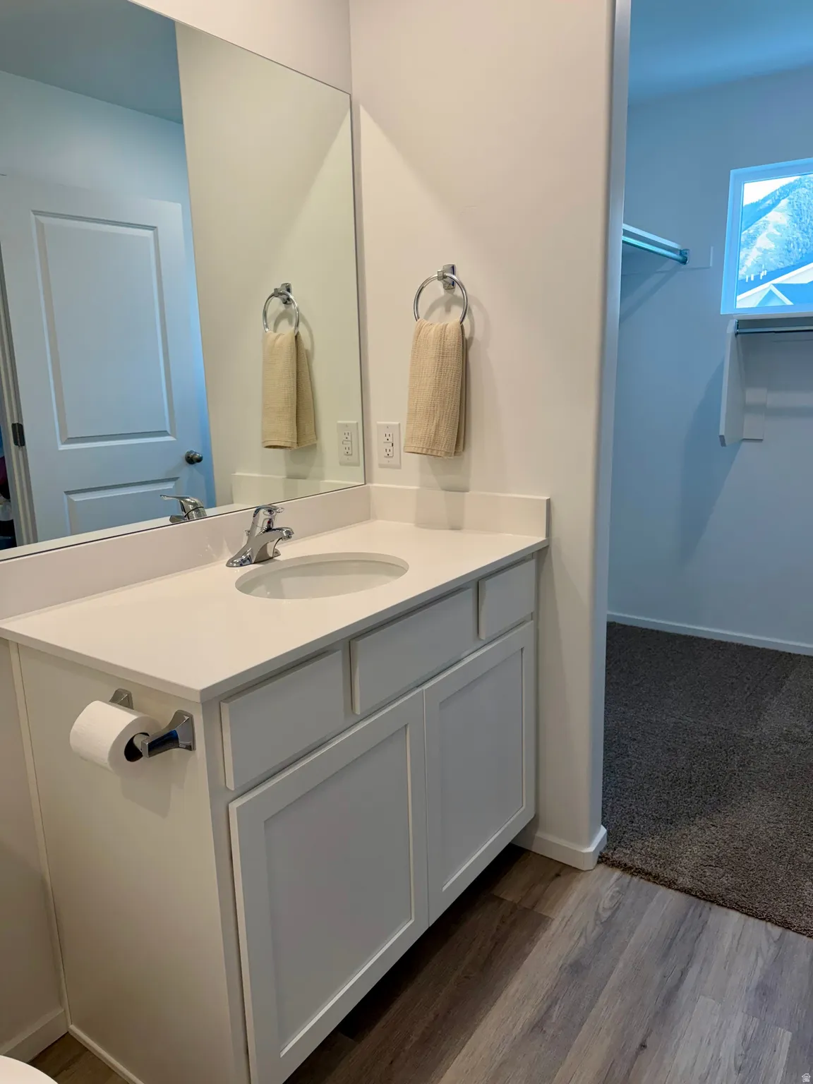 White vanity with undermount sink, solid surface countertop, and chrome faucet