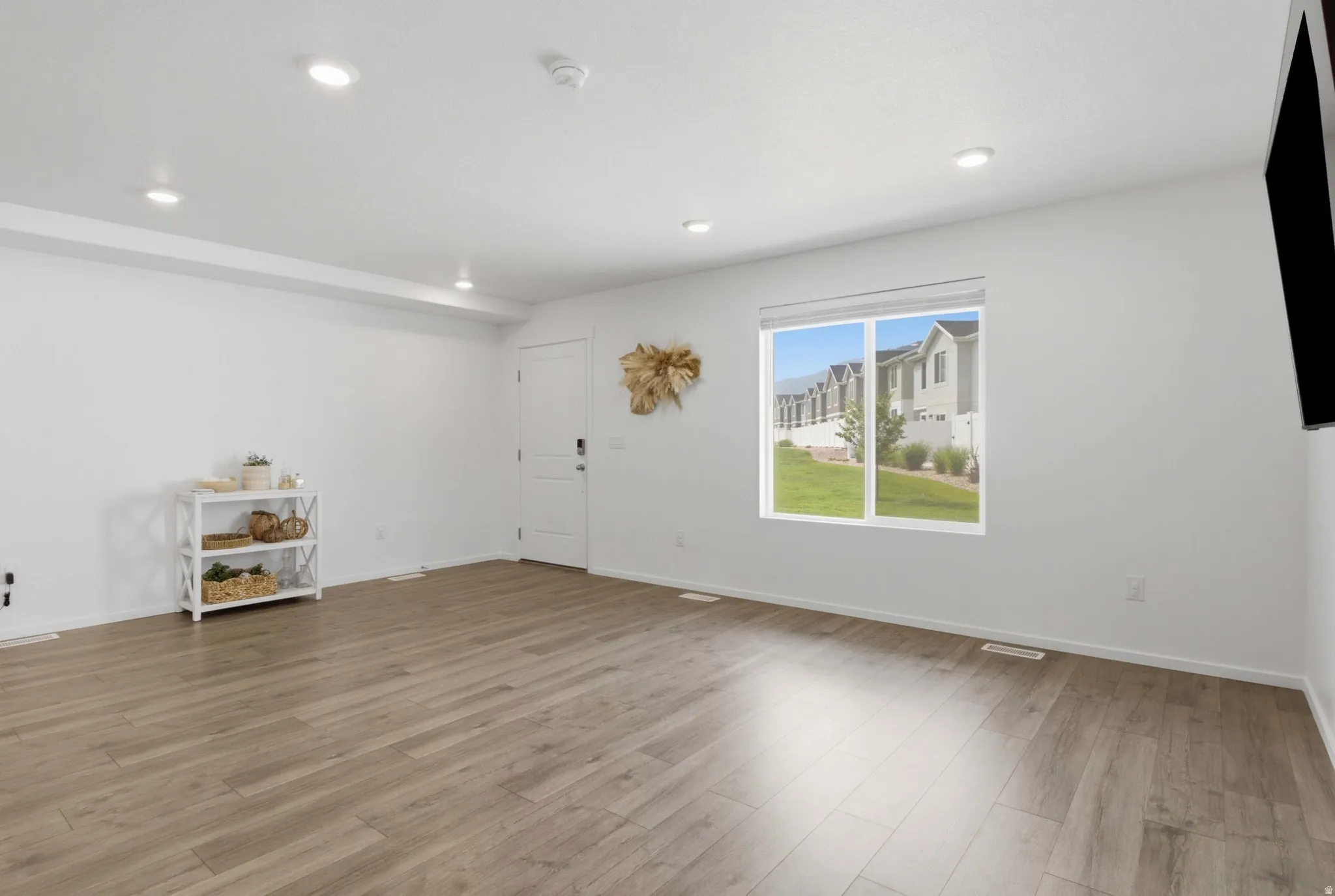 Bright living space with wood-finish flooring, recessed lighting, and a large window