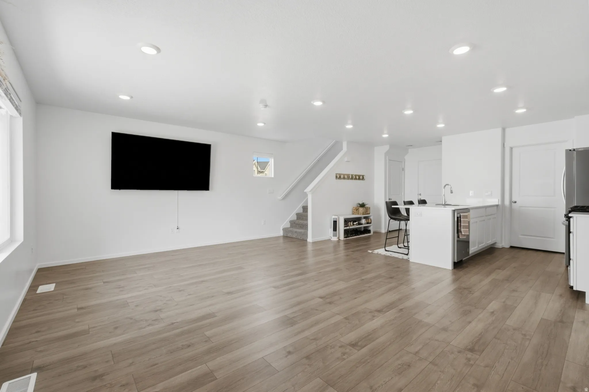 Open-concept living space featuring wood-finish flooring, recessed lighting, and white walls