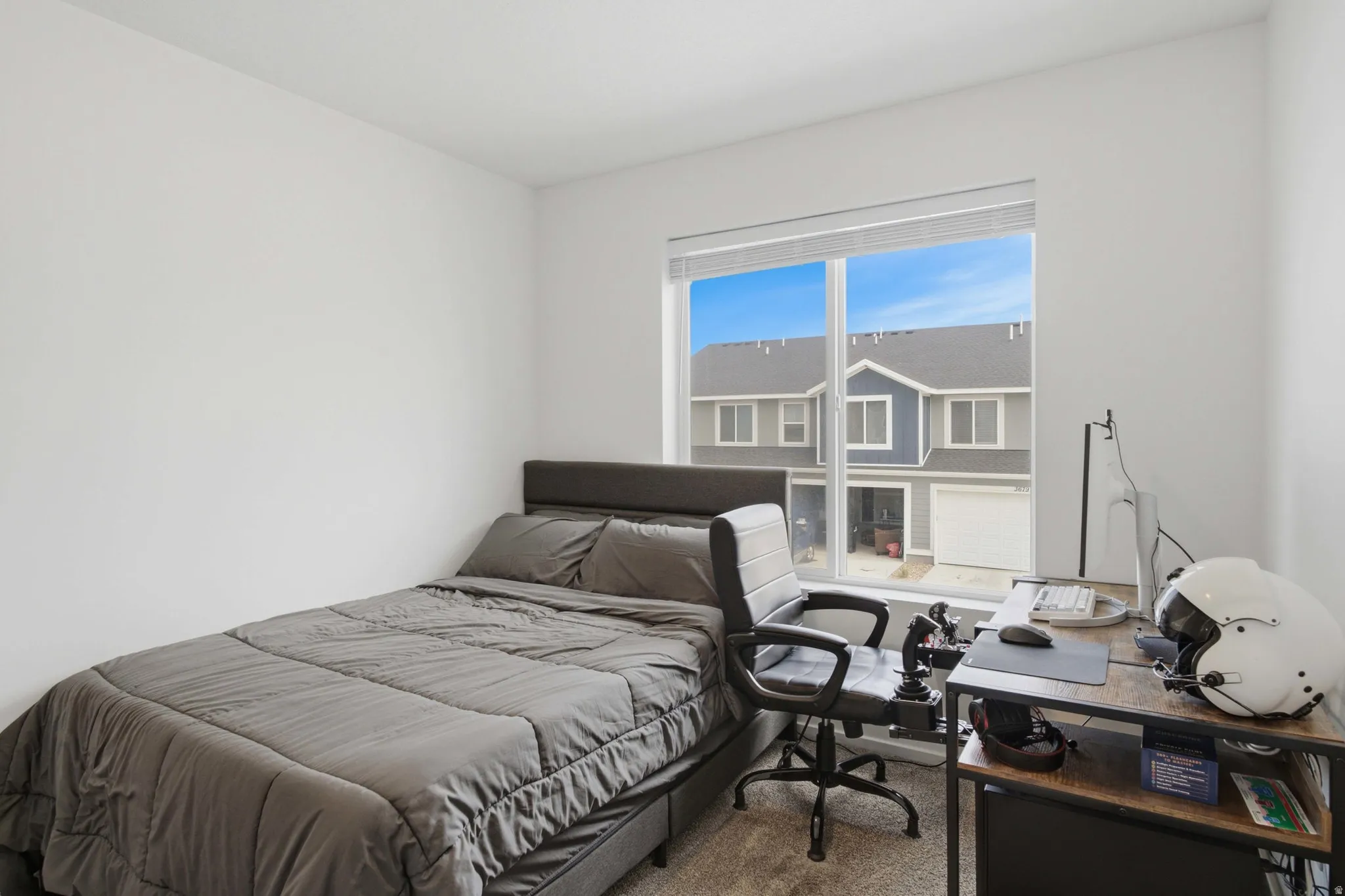 Carpeted room featuring a large window, white walls, and a built-in desk