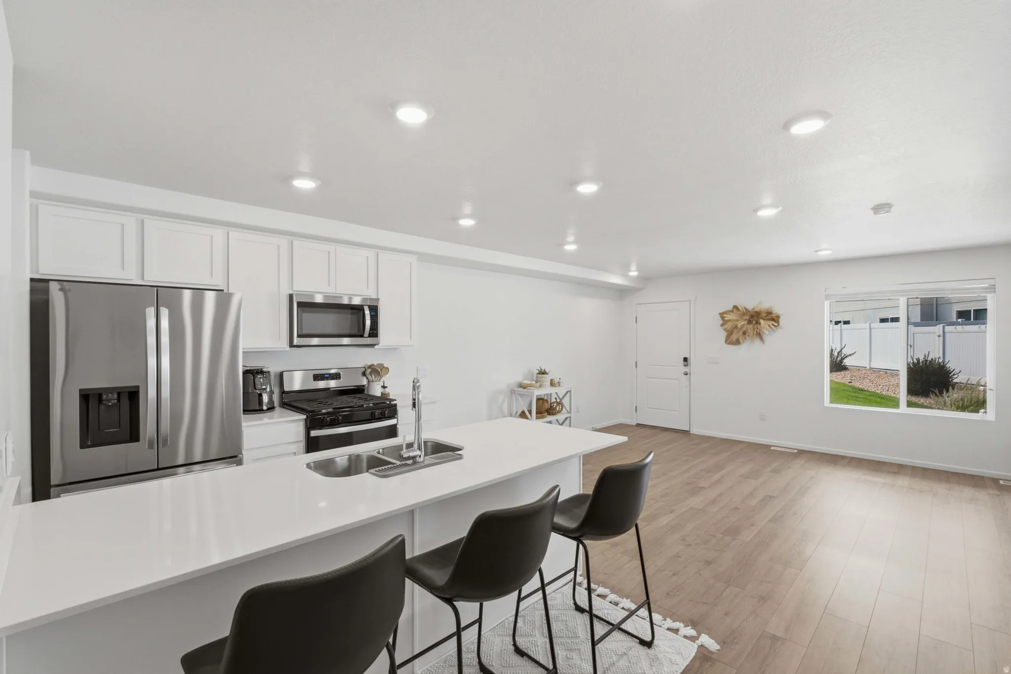 Modern kitchen featuring stainless steel appliances, white cabinetry, and a spacious island with a double sink