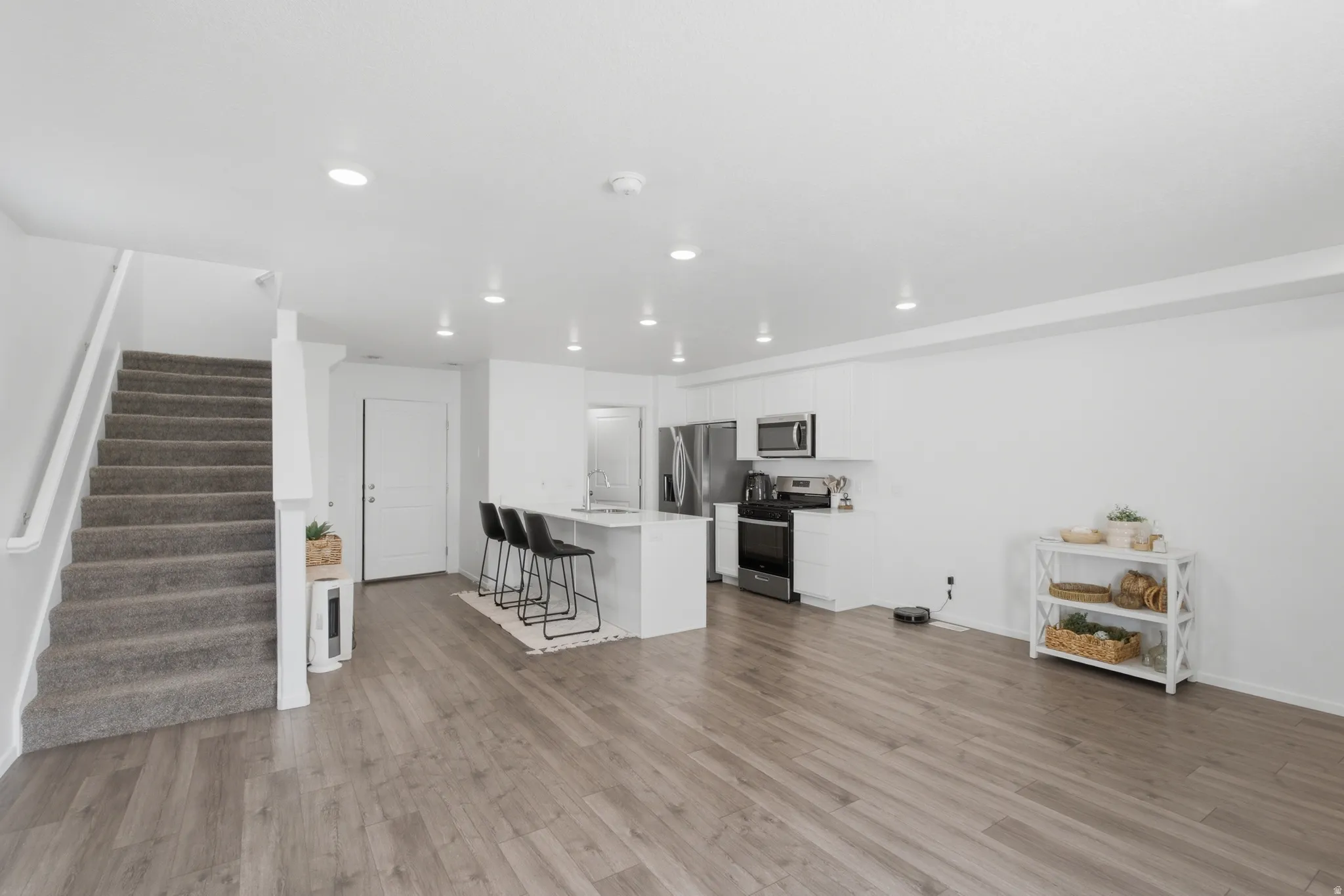 Open-concept living area featuring wood-finish flooring, recessed lighting, and a modern kitchen