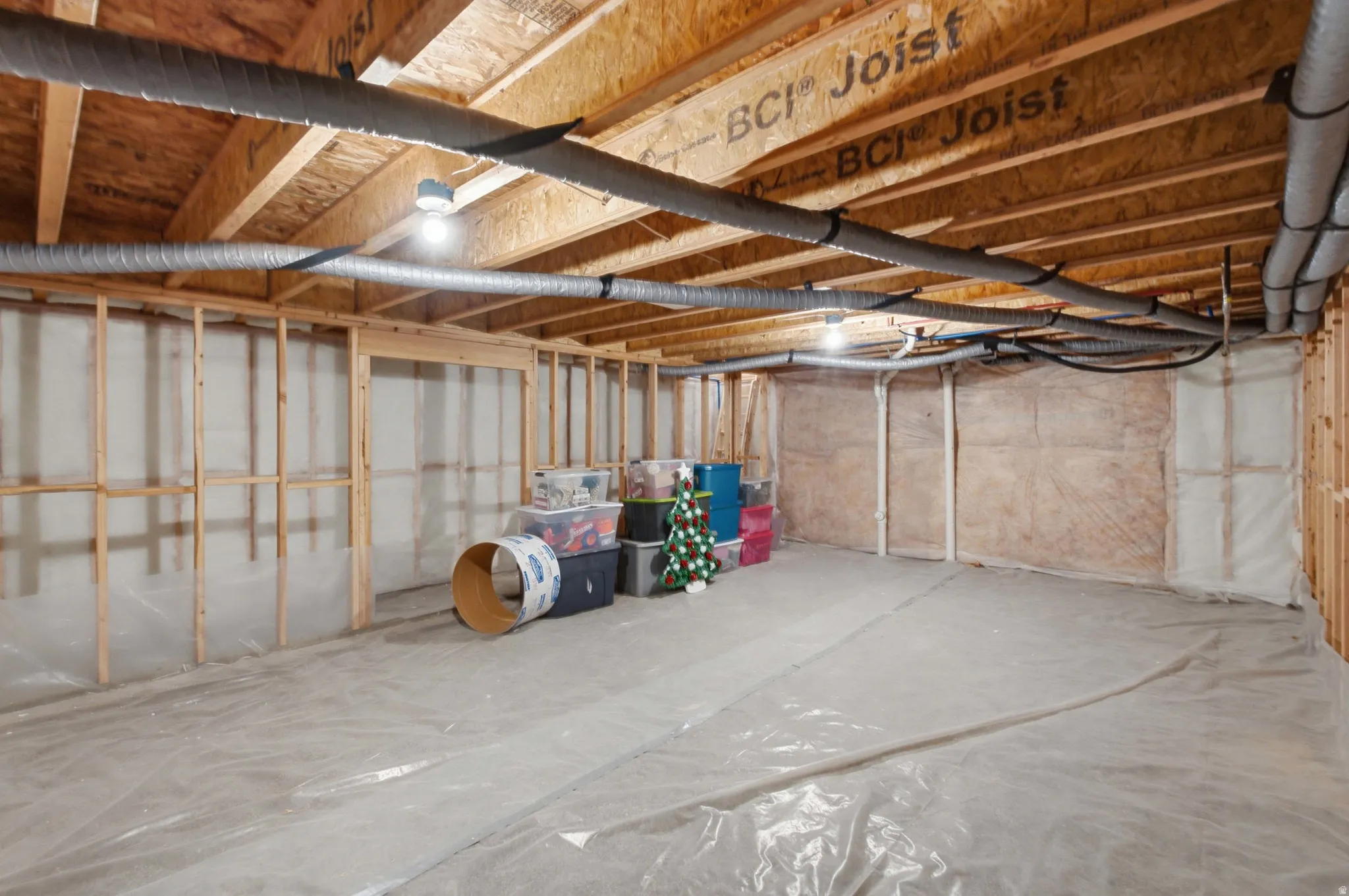 Basement featuring exposed wood joists, framed wall studs, and insulation