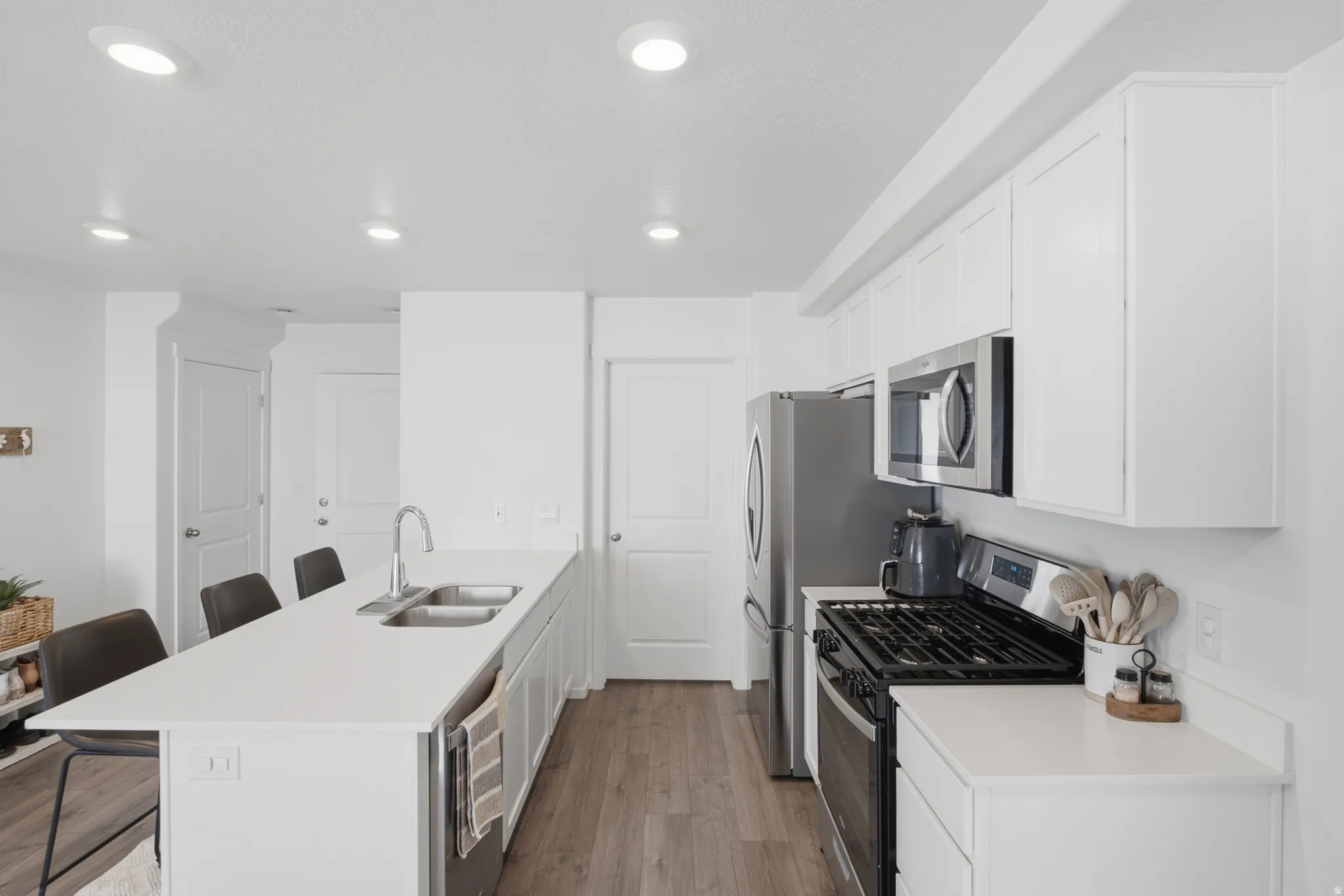 Contemporary kitchen featuring white cabinetry, light countertops, and wood-finish flooring