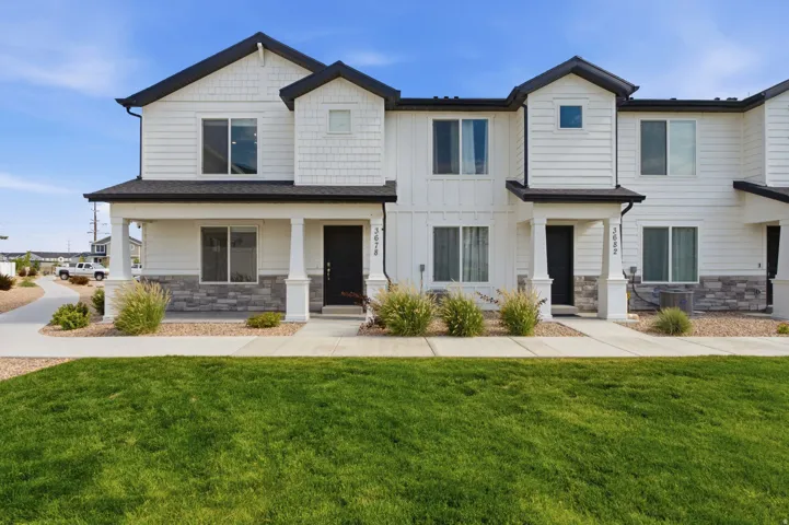 Modern multi-level exterior featuring white horizontal siding, dark roofline, and stone veneer accents