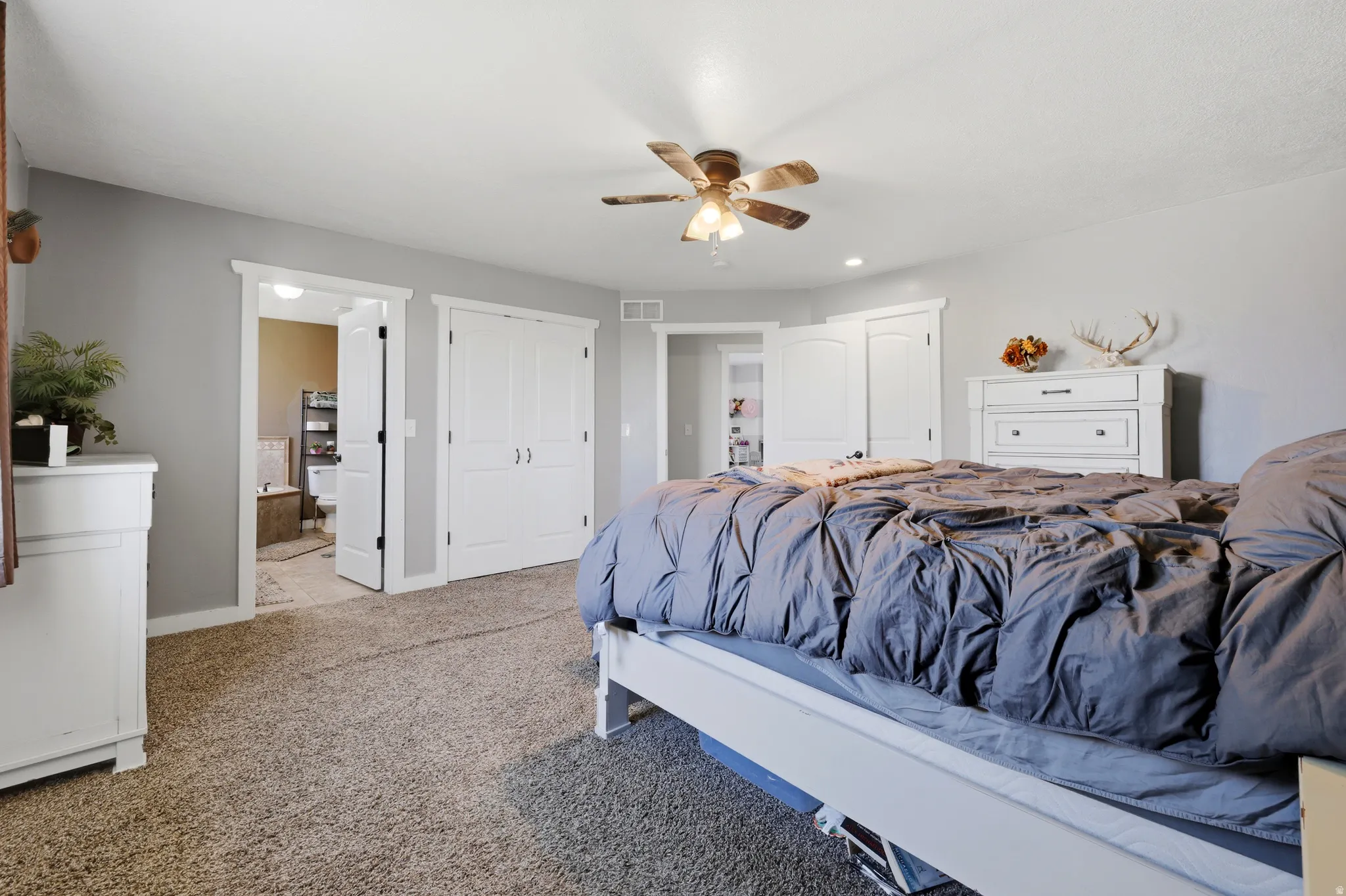 Carpeted bedroom with a ceiling fan, light gray walls, and white trim