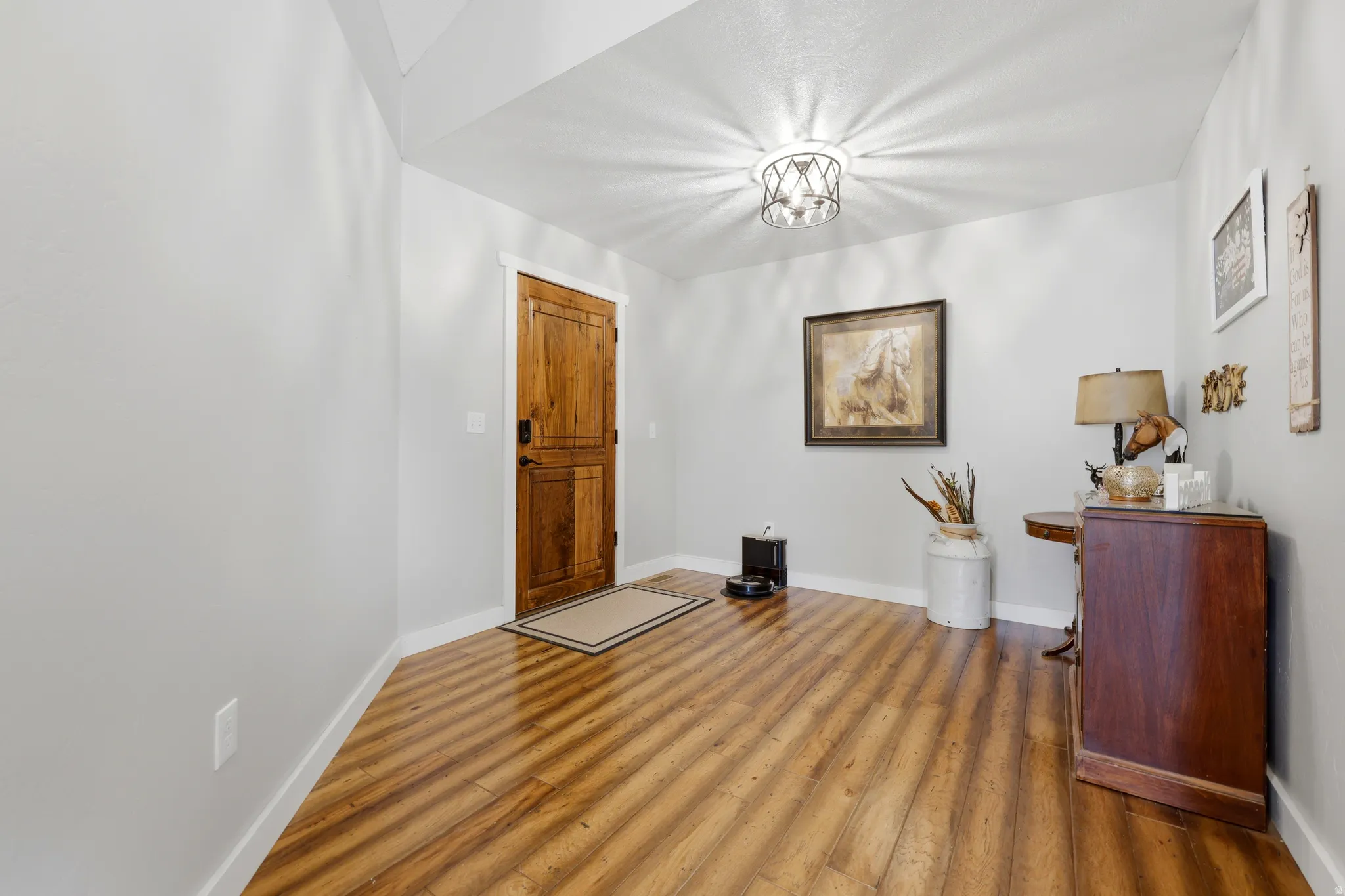 Entryway featuring wood-finish flooring, a solid wood door with white trim, and a decorative ceiling light fixture