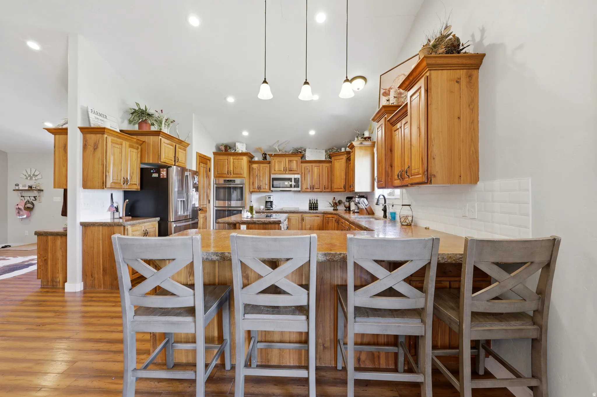 Spacious kitchen featuring extensive wood cabinetry, wood-finish flooring, and a kitchen island with built-in seating