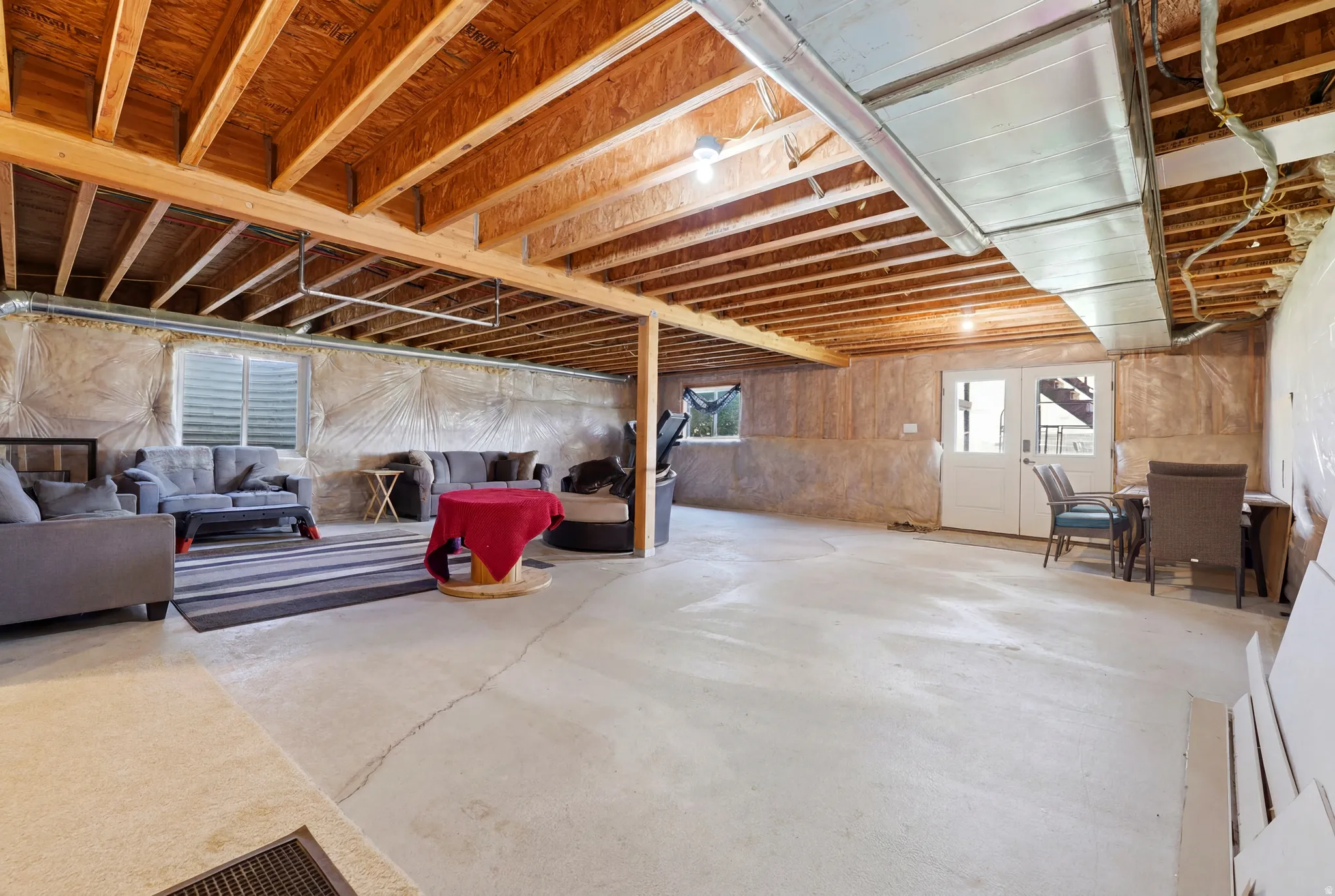 Unfinished basement featuring exposed wood joists and concrete flooring