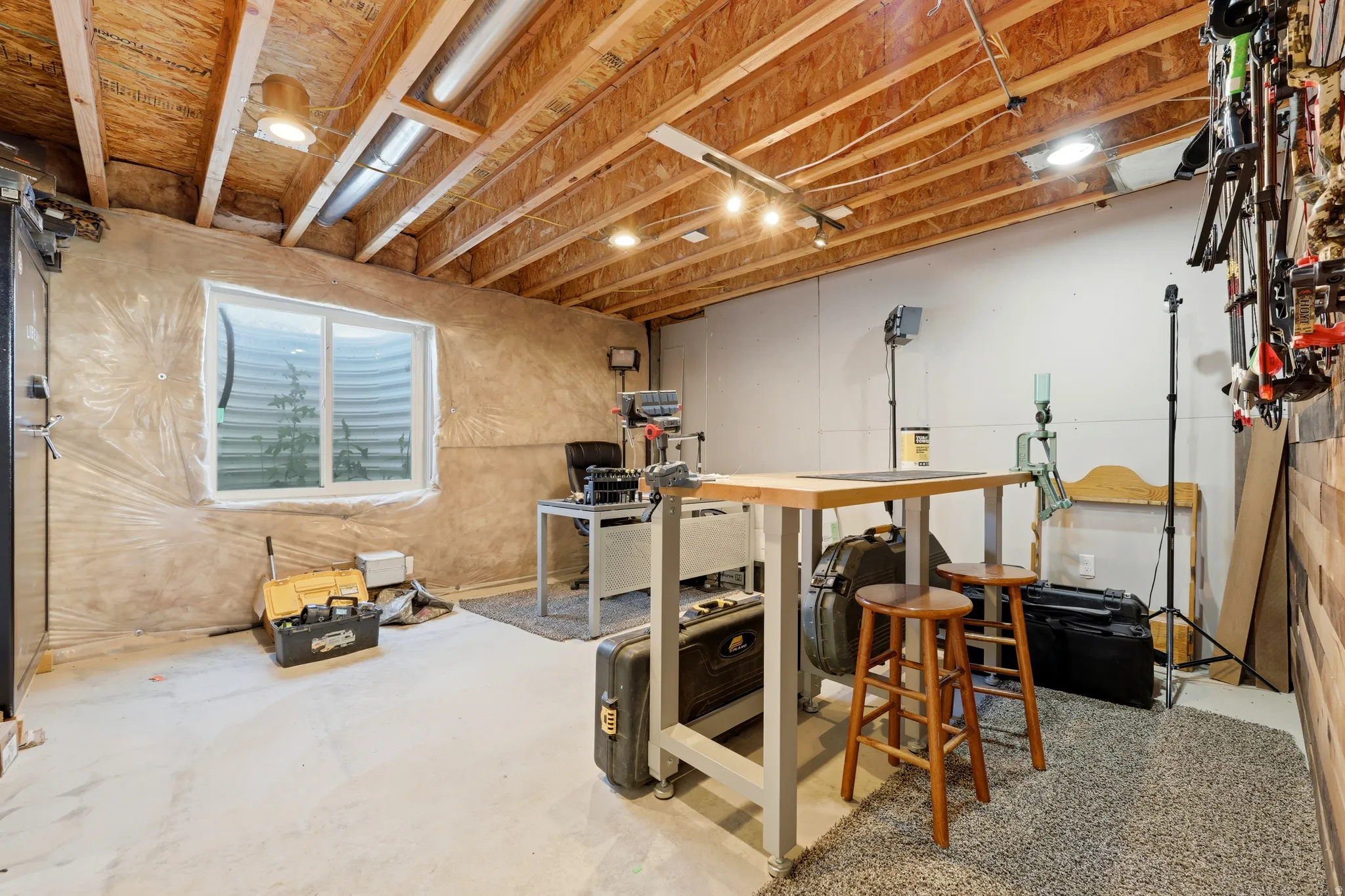 Unfinished basement space featuring exposed wood joists, concrete flooring, recessed lighting, and a white-framed egress window